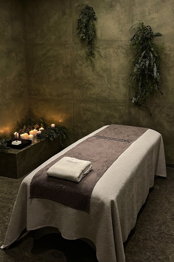 A treatment room lit by candles, with a made-up massage table